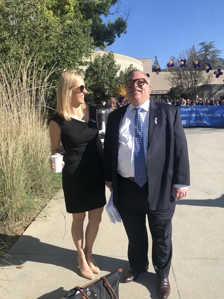 Man and woman smiling outdoors with coffee.
