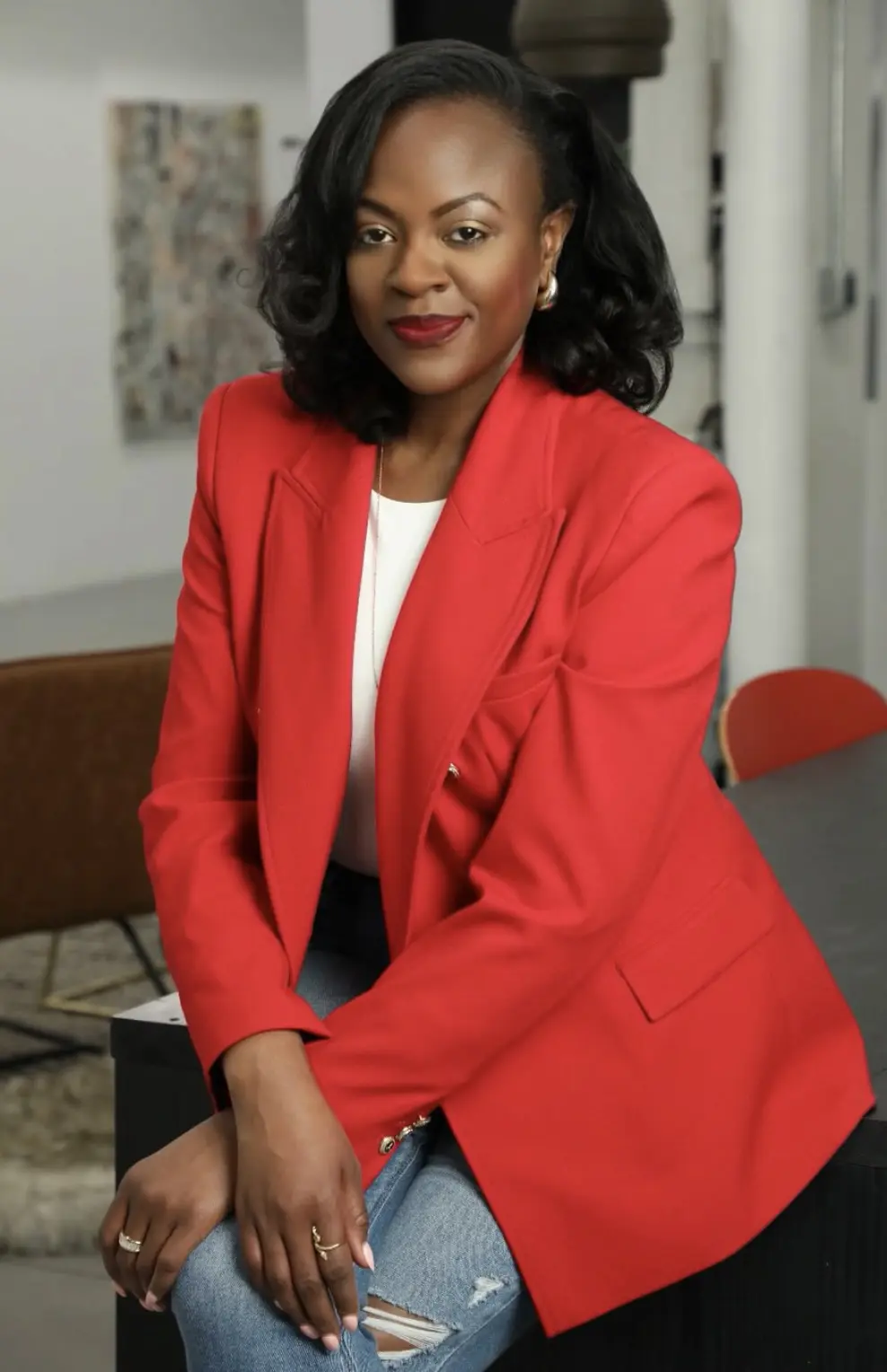 Person in red blazer sitting and smiling.