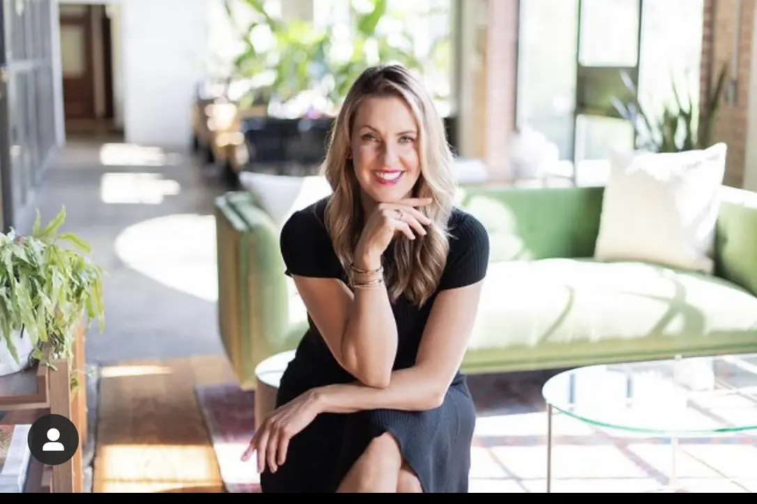 Smiling woman sitting in sunlit room.