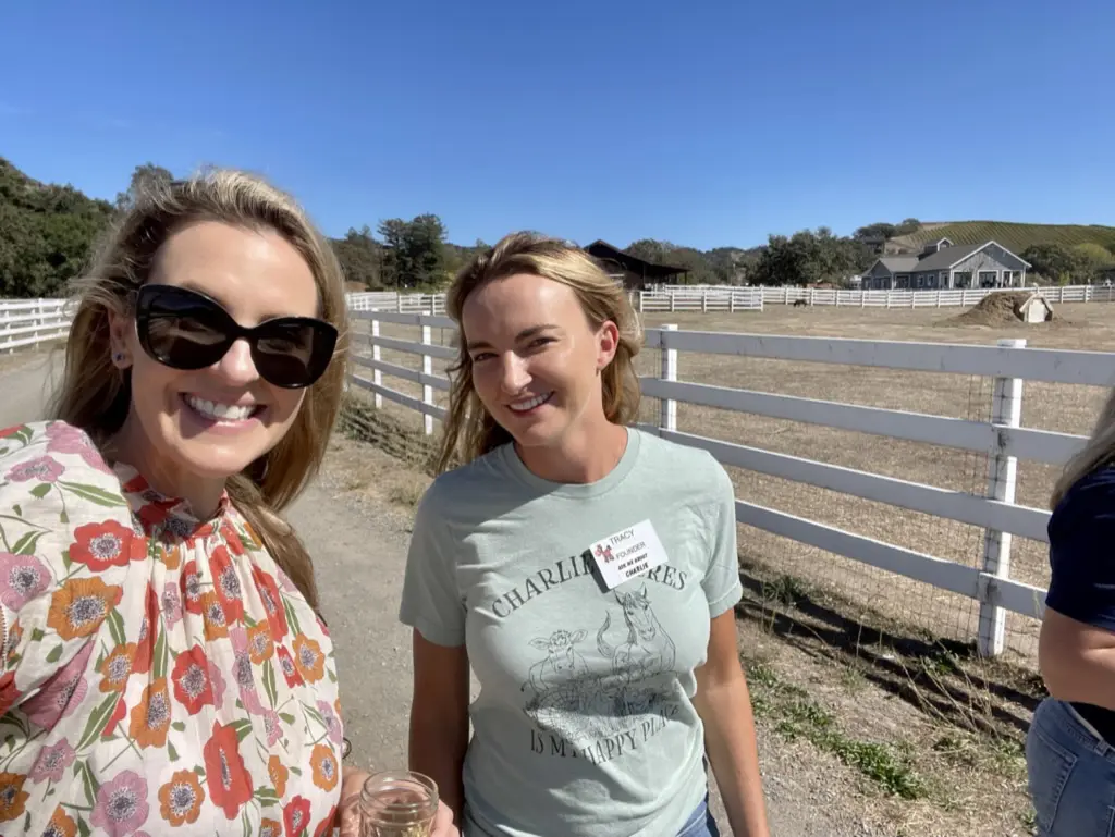 Two women smiling at a sunny farm.