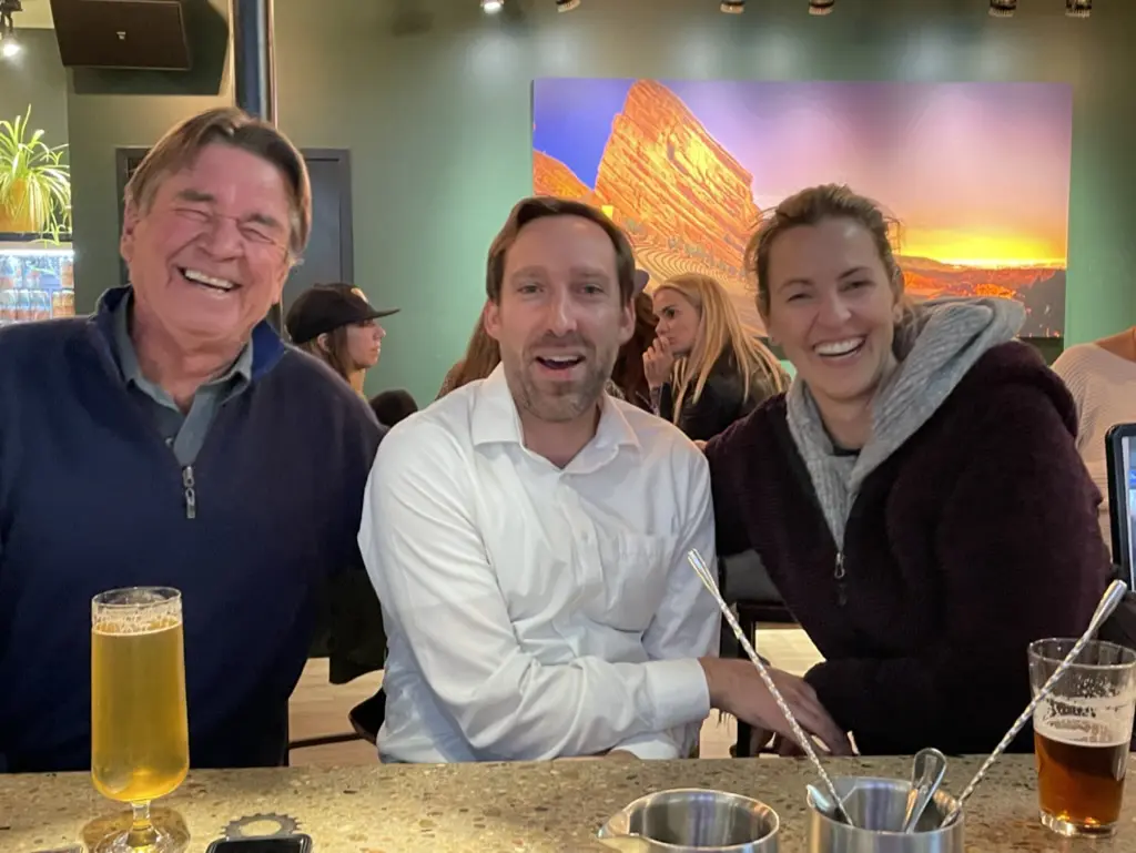 Three people smiling at a bar.