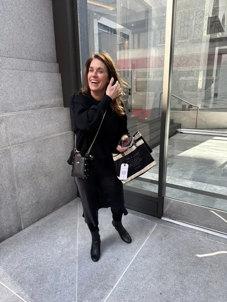 Woman smiling outside a modern glass building.