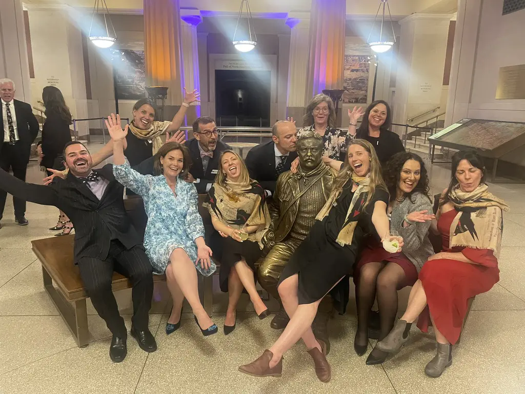 Group celebrating around a statue indoors.