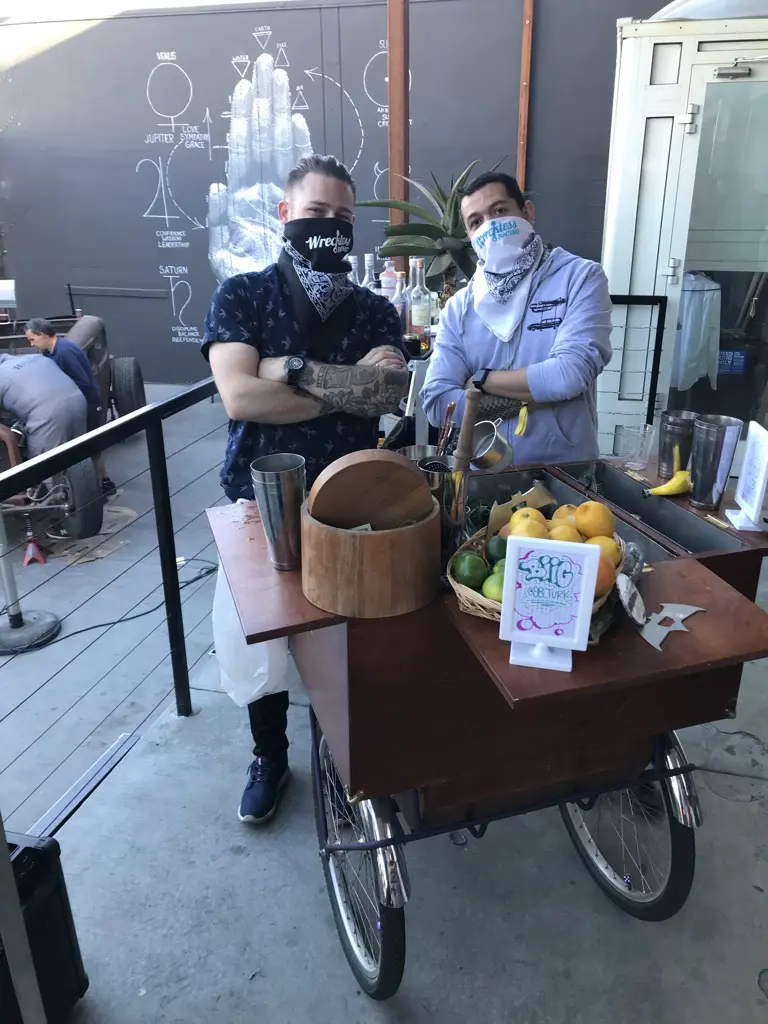 Two people behind a mobile fruit cart.