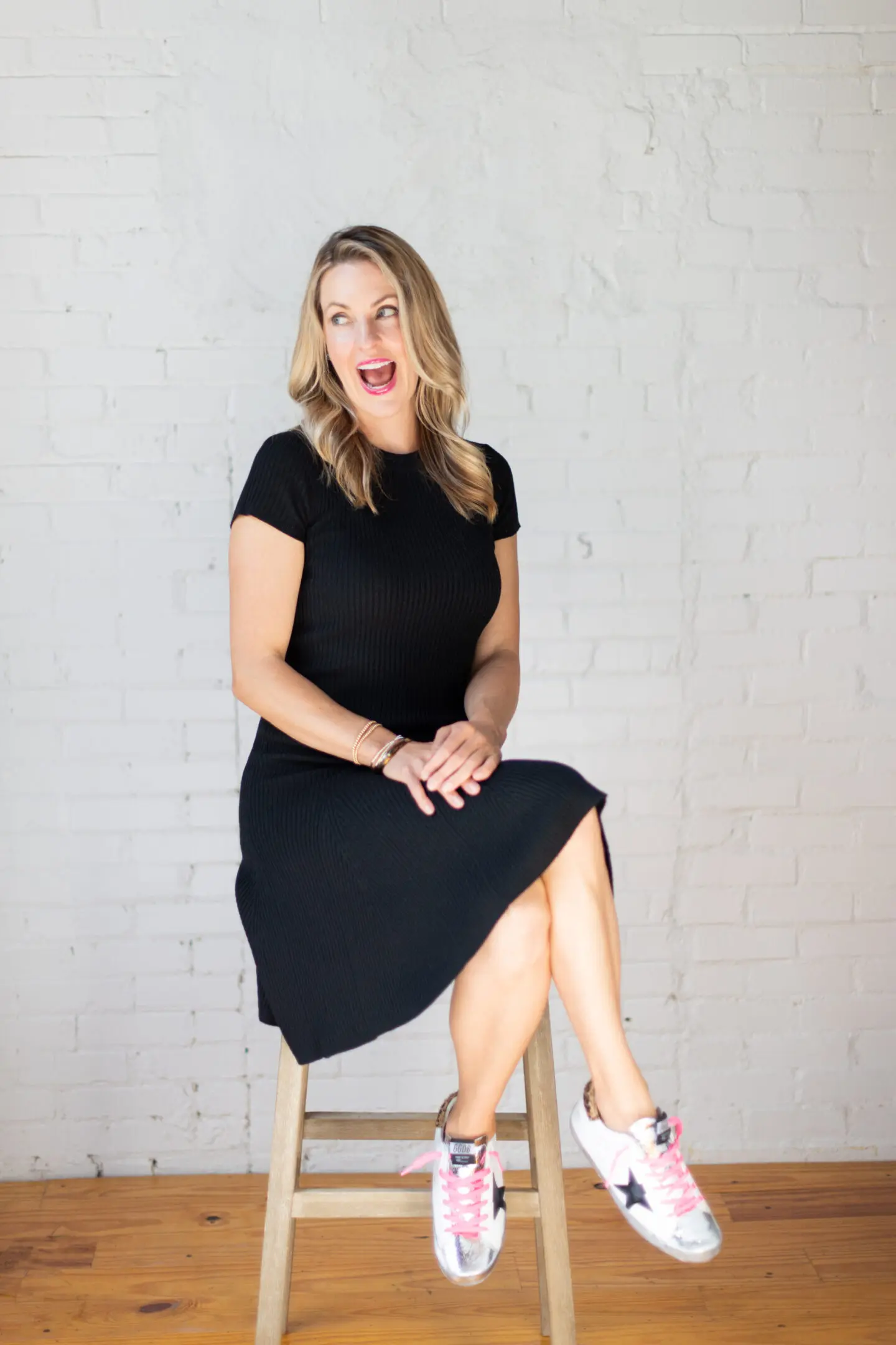 Woman smiling, sitting on a stool.