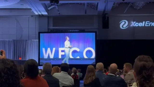 Person speaking on stage at conference event.